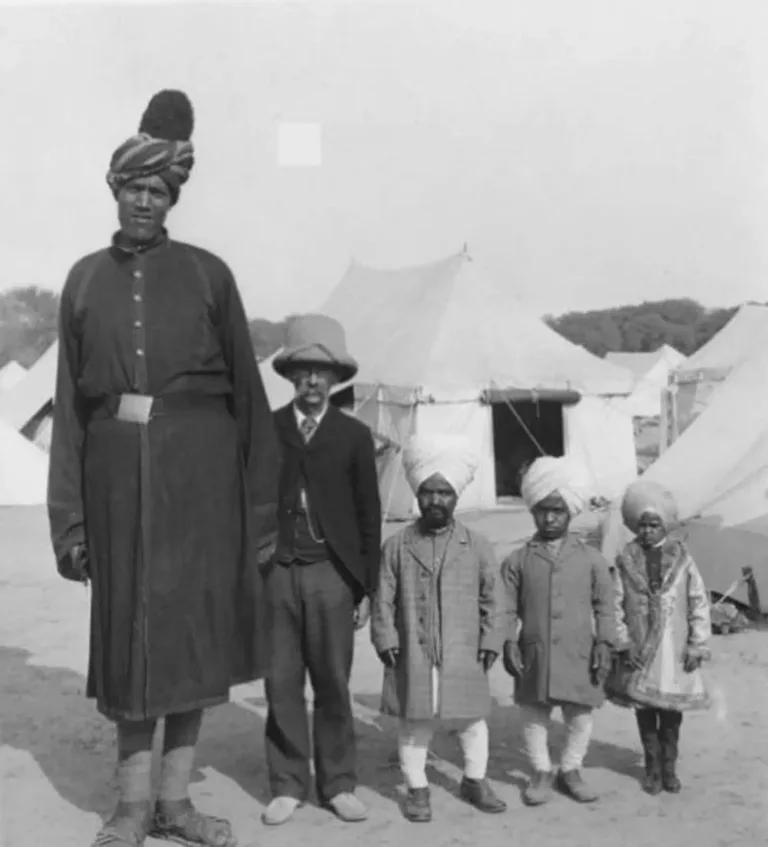 Professor Ricalton posing beside one of the Kashmir giants, highlighting dramatic height contrast
