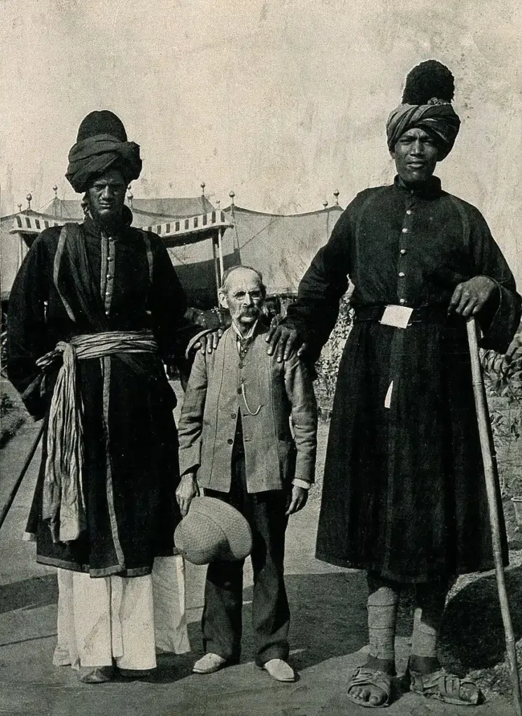 Two towering Kashmir giants standing beside Professor Ricalton, emphasizing their height difference